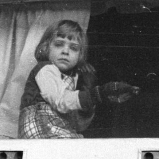 Child peering out of a window frame.