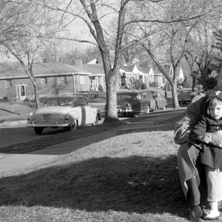 Family portrait by vintage cars, 1950s–60s.