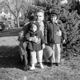 Family portrait by vintage cars, 1950s–60s.