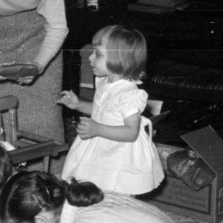 Family gathering around a Christmas tree opening gifts.
