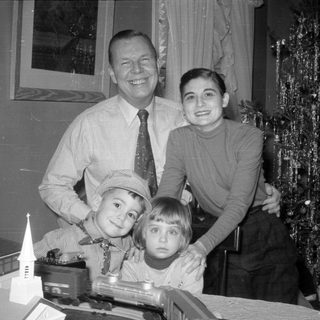 Family posing with model trains and Christmas tree.