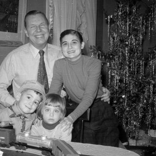 Family posing with model trains and Christmas tree.