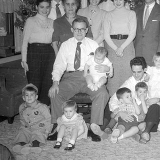 Multi-generational group portrait in a living room by a Christmas tree.