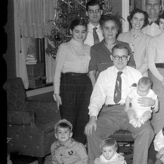 Multi-generational group portrait in a living room by a Christmas tree.