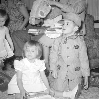 Three children in formal wear on a carpeted floor.
