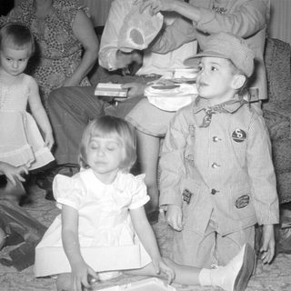 Three children in formal wear on a carpeted floor.