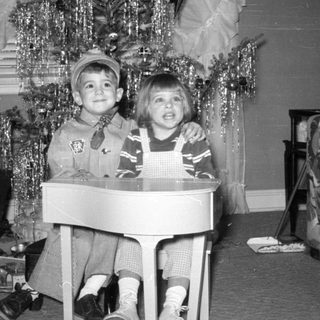 Two children posing by a decorated Christmas tree.