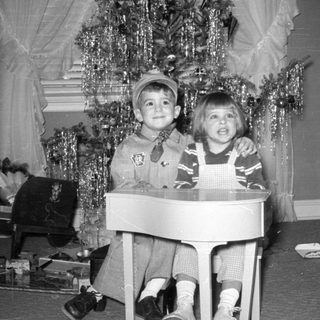 Two children posing by a decorated Christmas tree.