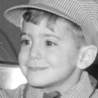 Boy in conductor outfit with model train set.