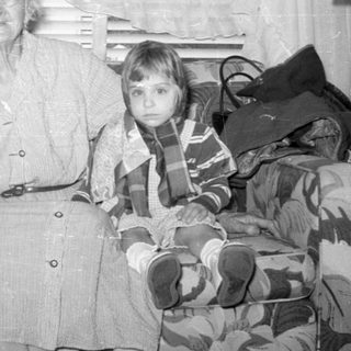 Older woman and two children on a patterned sofa.