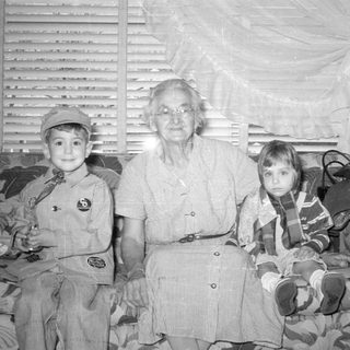 Older woman and two children on a patterned sofa.