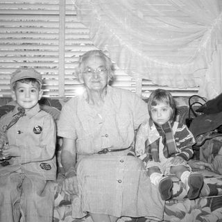 Older woman and two children on a patterned sofa.