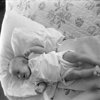 Infant lying on a pillow and patterned quilt.