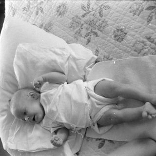 Infant lying on a pillow and patterned quilt.