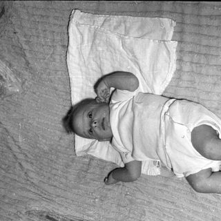 Infant lying on ribbed fabric and white cloth.