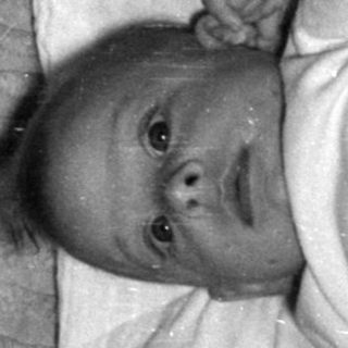 Infant lying on ribbed fabric and white cloth.