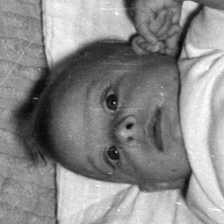 Infant lying on ribbed fabric and white cloth.