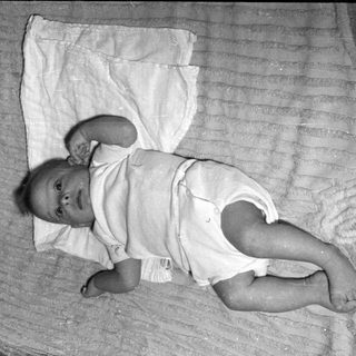 Infant lying on ribbed fabric and white cloth.
