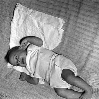 Infant lying on a striped blanket and white cloth.