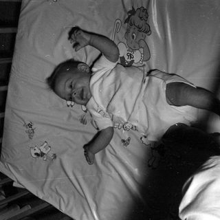 Infant lying in a wooden crib.