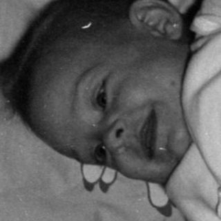 Infant lying in a wooden crib.