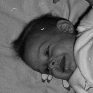 Infant lying in a wooden crib.