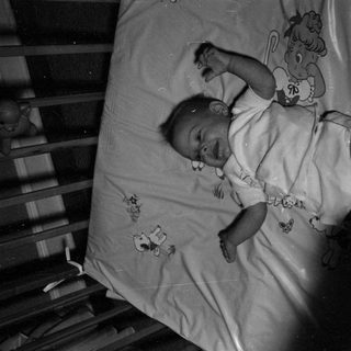 Infant lying in a wooden crib.