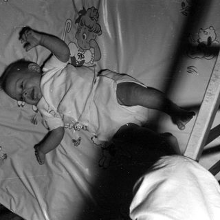 Infant lying in a wooden crib.