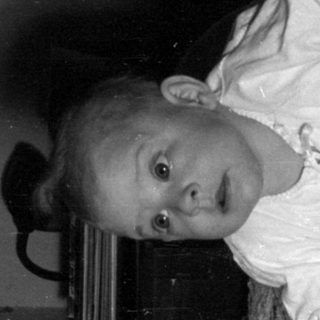 Infant lying on a textured blanket in a room.
