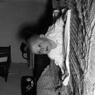 Infant lying on a textured blanket in a room.