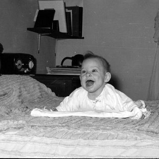 Baby lying on a bed in a domestic room.