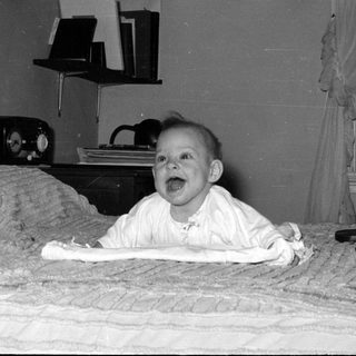 Baby lying on a bed in a domestic room.