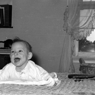 Baby lying on a bed in a domestic room.
