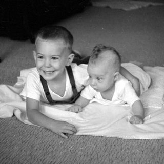 Two young children lying on a white blanket.