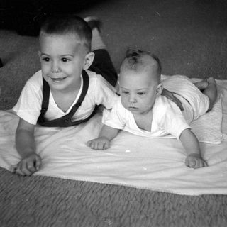 Two young children lying on a white cloth.
