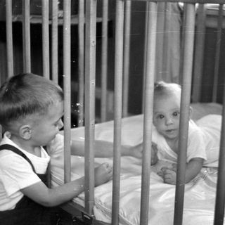 Young child looking at an infant in a crib.