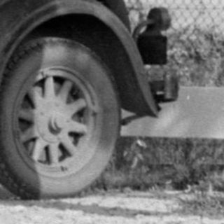 Man and woman sitting on a vintage car bumper.