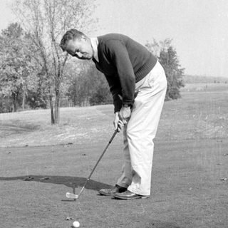 Man preparing to hit a golf ball outdoors.