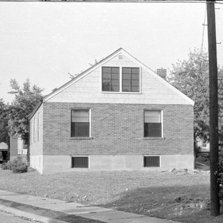 Small brick house with white gabled roof.