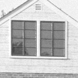 Small brick house with white gabled roof.