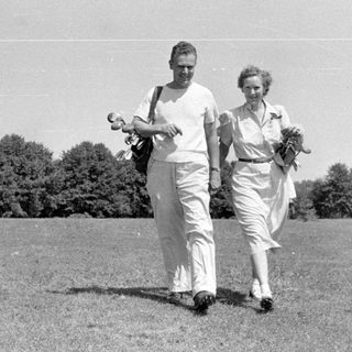 Man and woman walking in a grassy field.