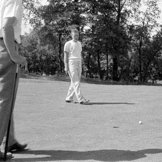 Three people on a golf course green.