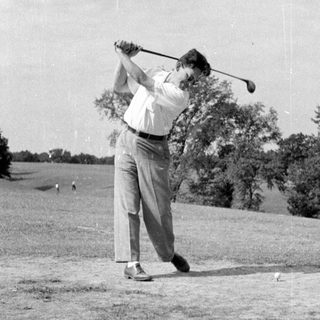 Man swinging a golf club on a course.
