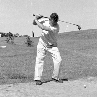 Man swinging a golf club on a course.
