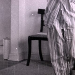 Woman in striped pajamas standing in a bedroom.