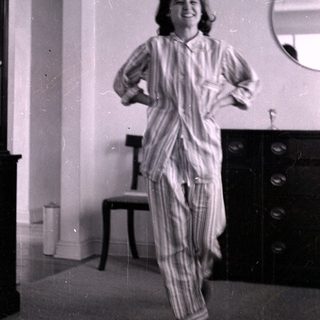 Woman in striped pajamas standing in a bedroom.