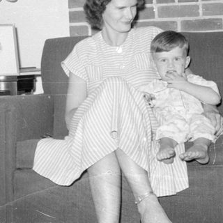 Woman and child sitting on a sofa by a fireplace.