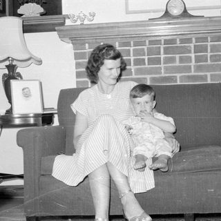 Woman and child sitting on a sofa by a fireplace.
