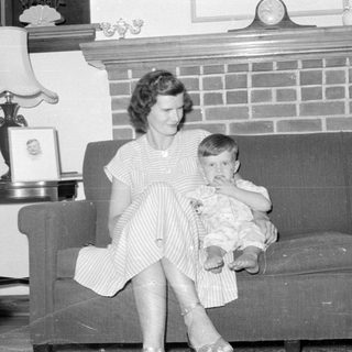 Woman and child sitting on a sofa by a fireplace.
