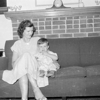 Woman and child sitting on a sofa by a fireplace.